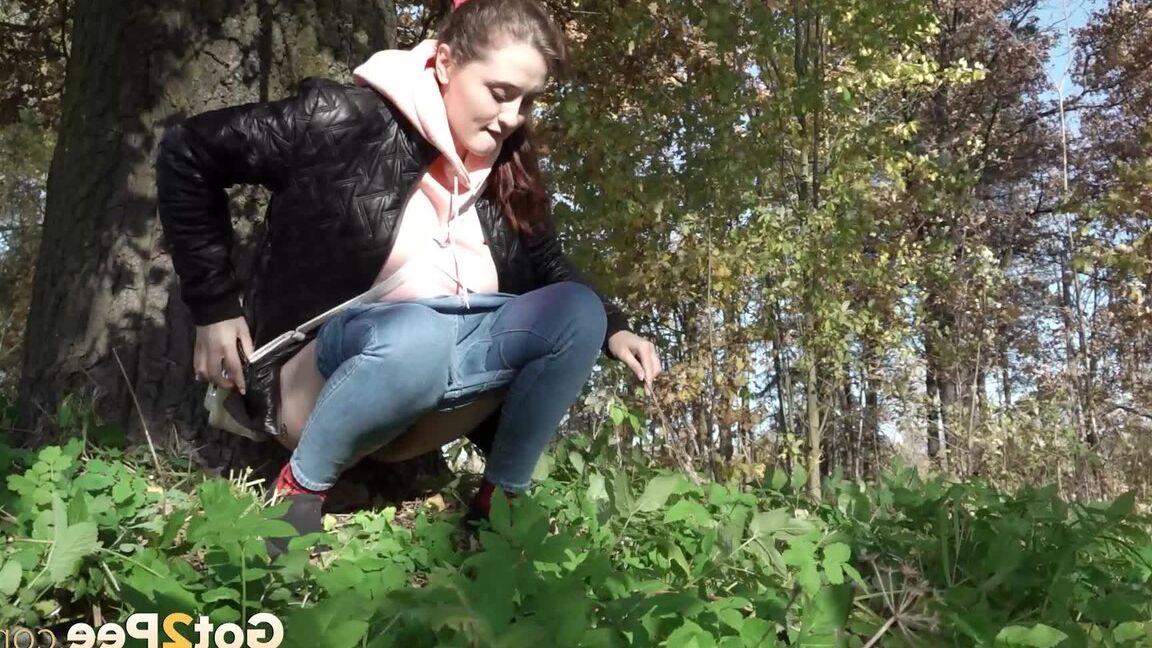 15P Kurz genommenes Mädel zieht ihre Jeans herunter, um neben einen Baum zu pinkeln
