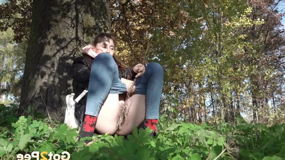 15P Kurz genommenes Mädel zieht ihre Jeans herunter, um neben einen Baum zu pinkeln