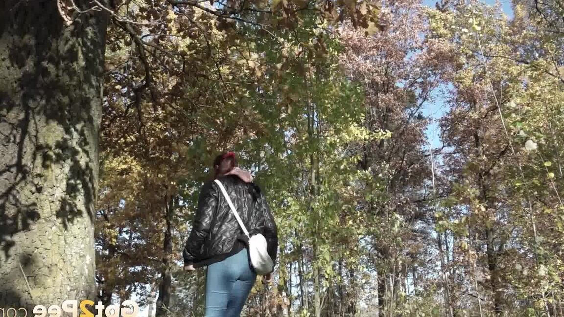 15P Kurz genommenes Mädel zieht ihre Jeans herunter, um neben einen Baum zu pinkeln