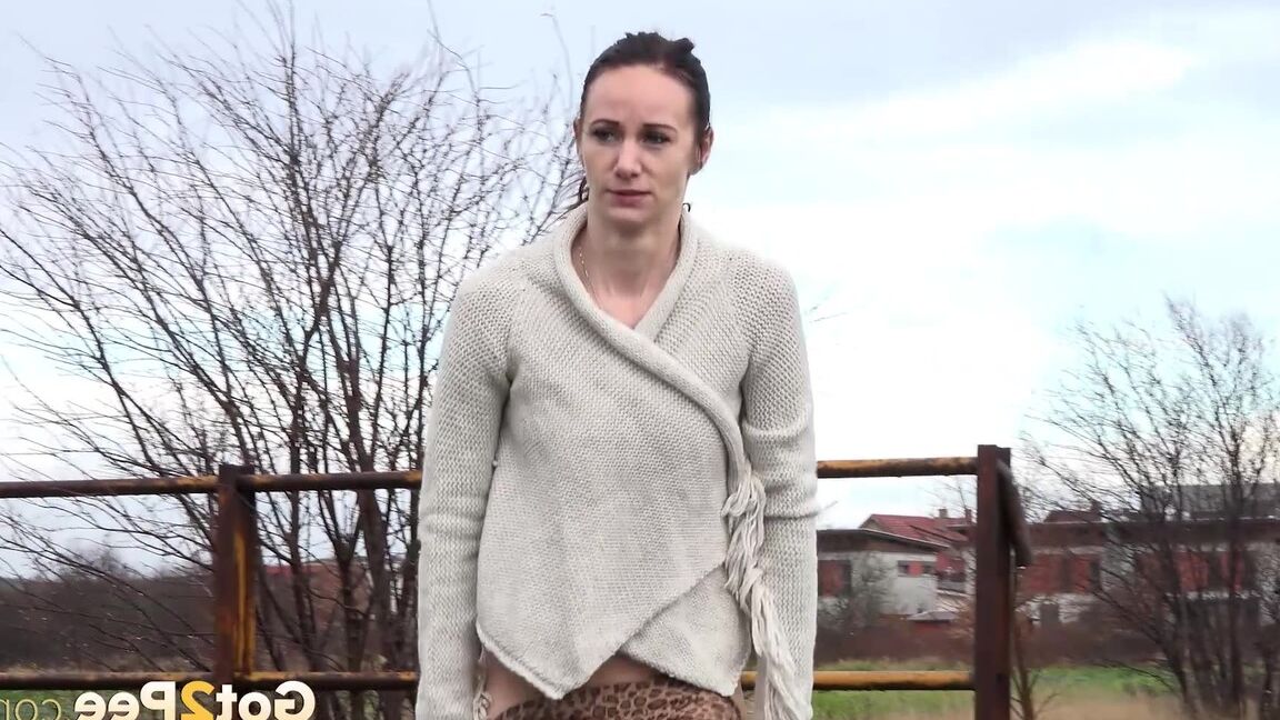 15P Short taken girl Eveline Neill pees on a paved path on a wet and dreary day