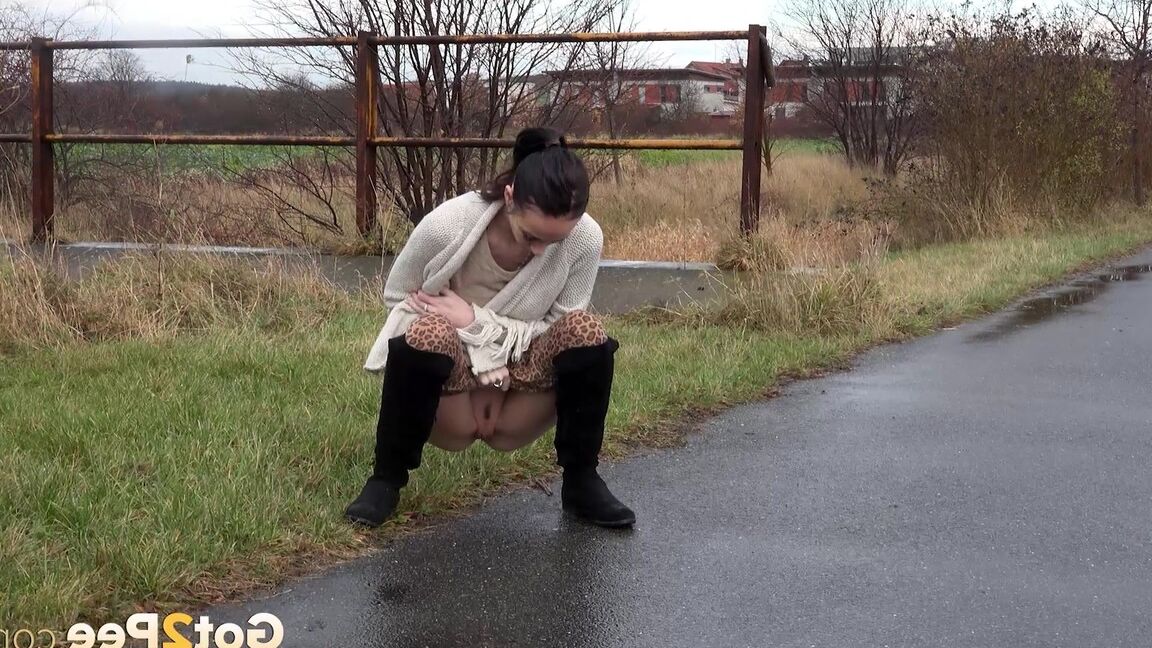 15P Short taken girl Eveline Neill pees on a paved path on a wet and dreary day