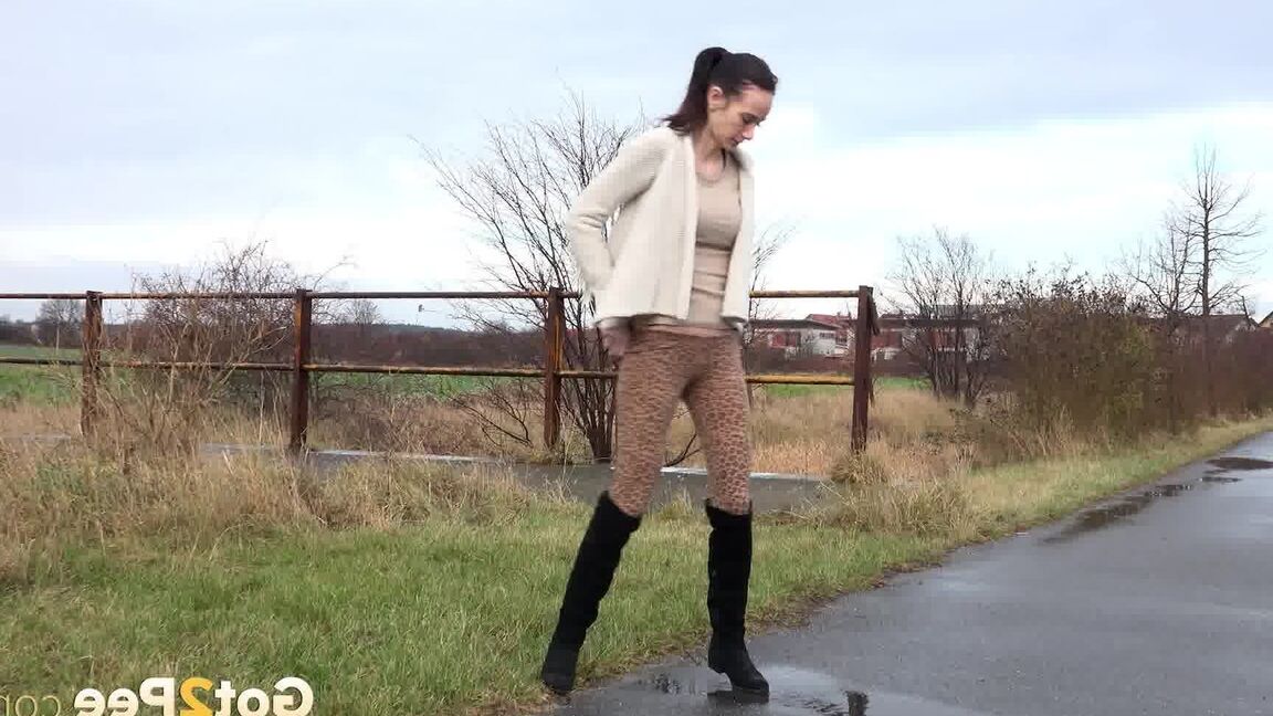 15P Short taken girl Eveline Neill pees on a paved path on a wet and dreary day