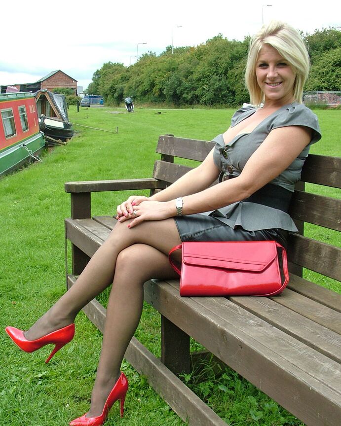 16P Une femme vêtue aux cheveux blonds montre ses escarpins rouges en bas nylon sur un banc