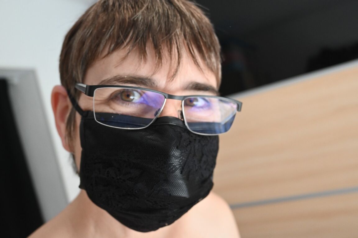 16P Amador nu com cabelo curto coloca uma máscara facial antes de começar a se vestir