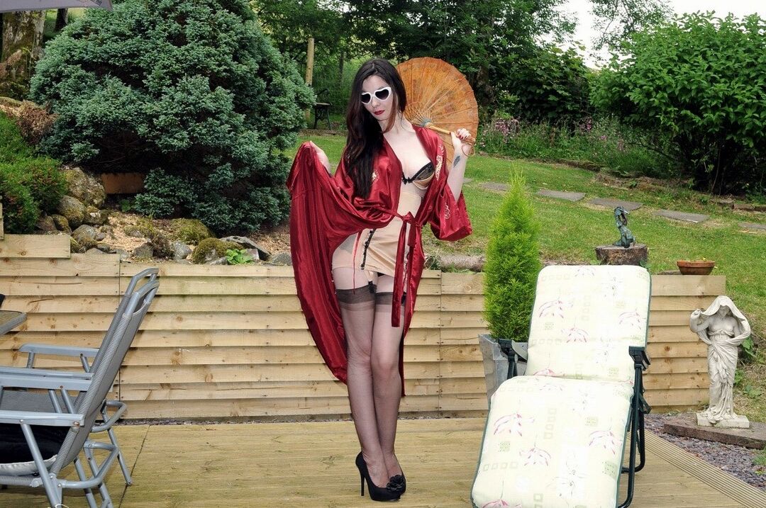 15P Dark haired woman lets a boob loose while modeling sheer nylons on patio