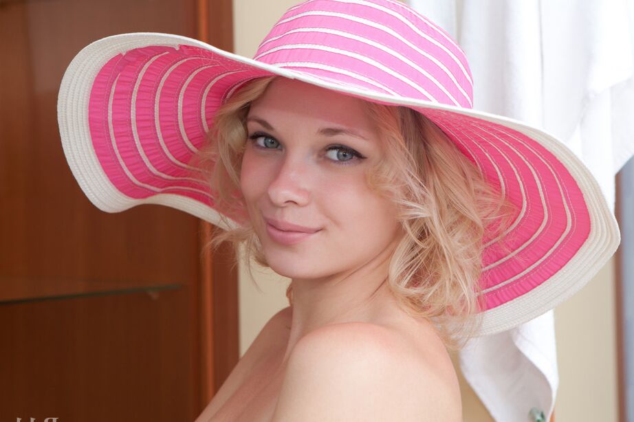 16P L'adorable jeune blonde Feeona prend de superbes poses nues avec un chapeau de soleil à larges bords.
