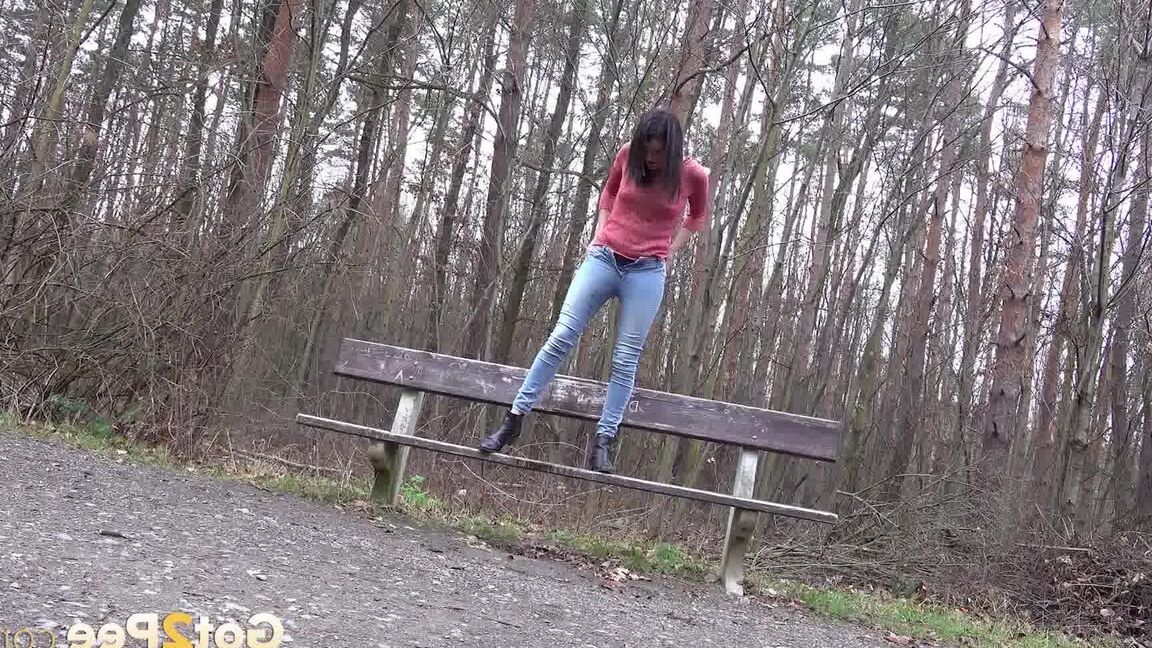 15P Tiny Tina squats on a wooden bench alongside a path for an urgent piss