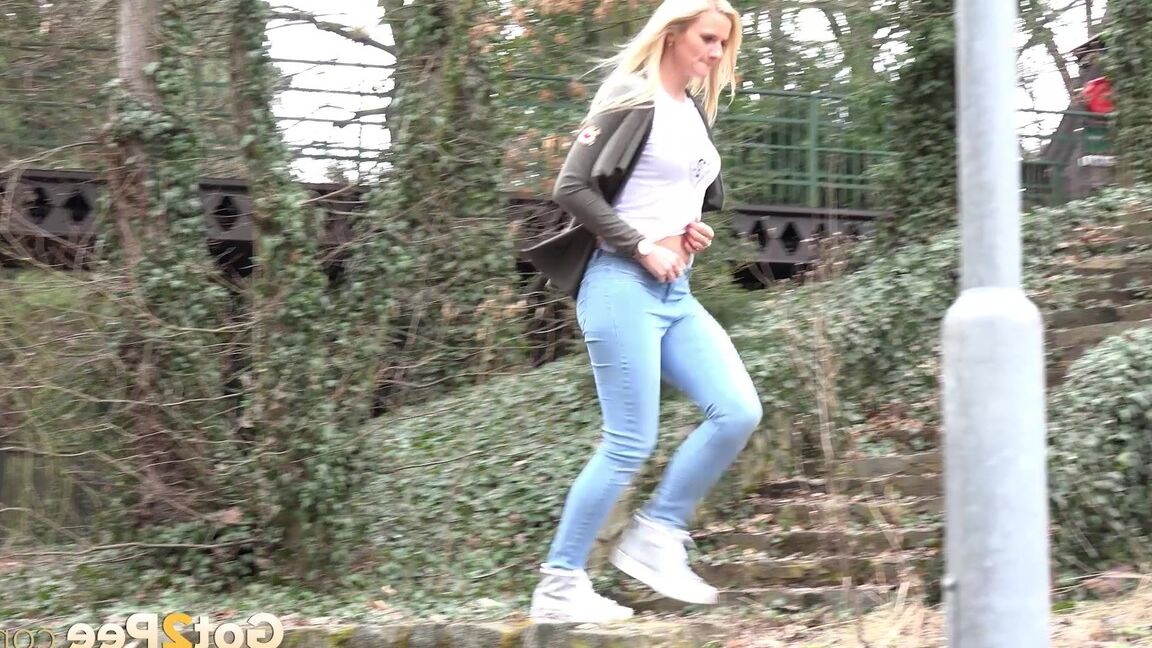 15P Jovem com longos cabelos loiros Katy Sky abaixa a calça jeans para fazer xixi lá fora