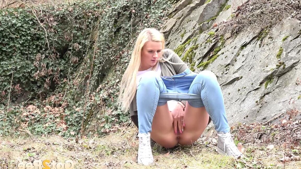 15P Jovem com longos cabelos loiros Katy Sky abaixa a calça jeans para fazer xixi lá fora