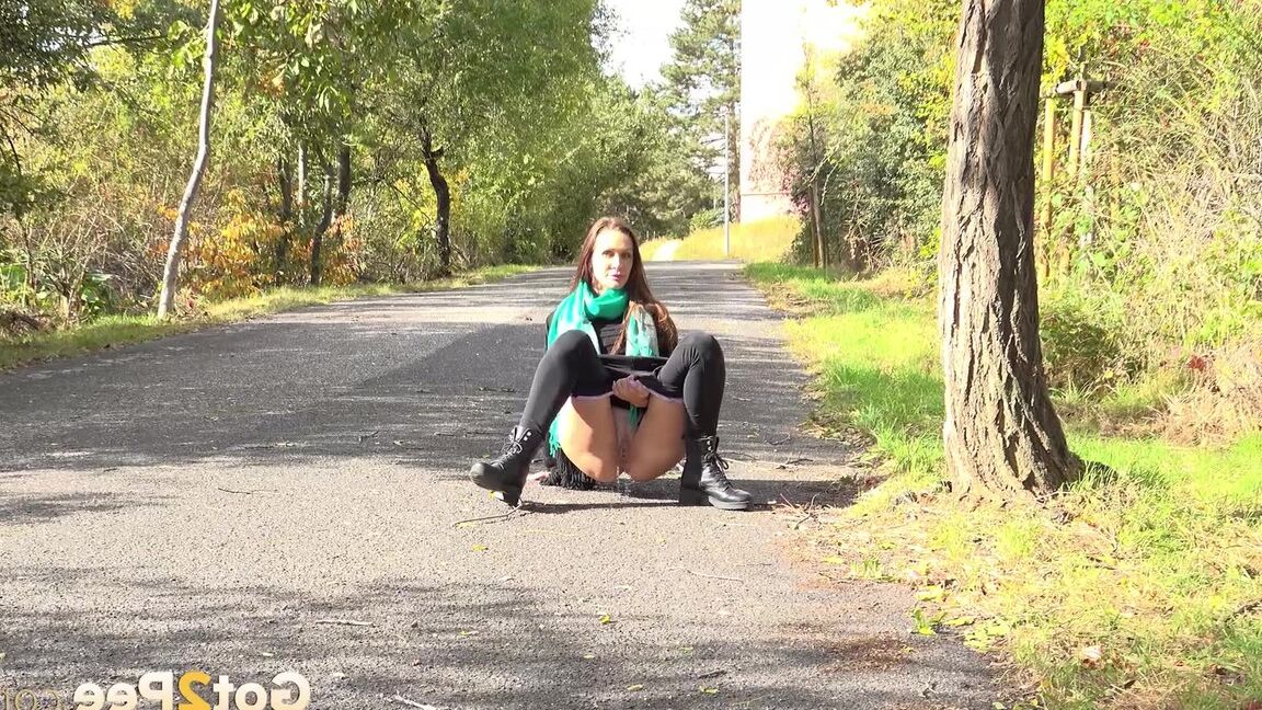 15P Caucasian girl Cynthia Vellons takes a piss while walking along a paved road