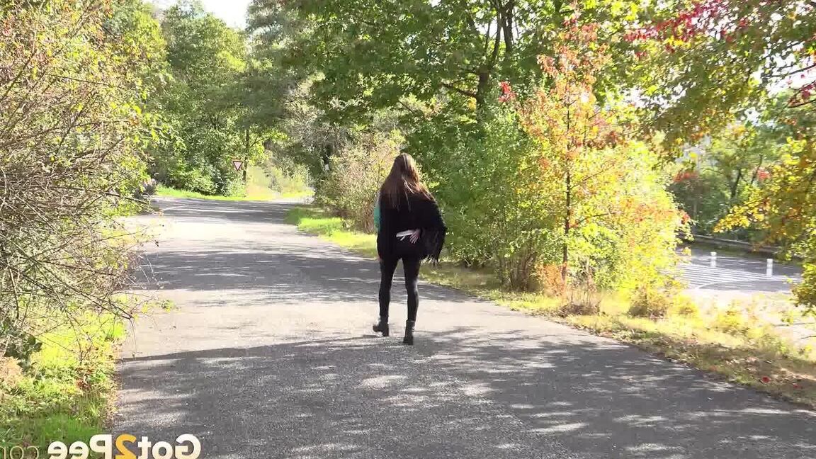 15P Caucasian girl Cynthia Vellons takes a piss while walking along a paved road