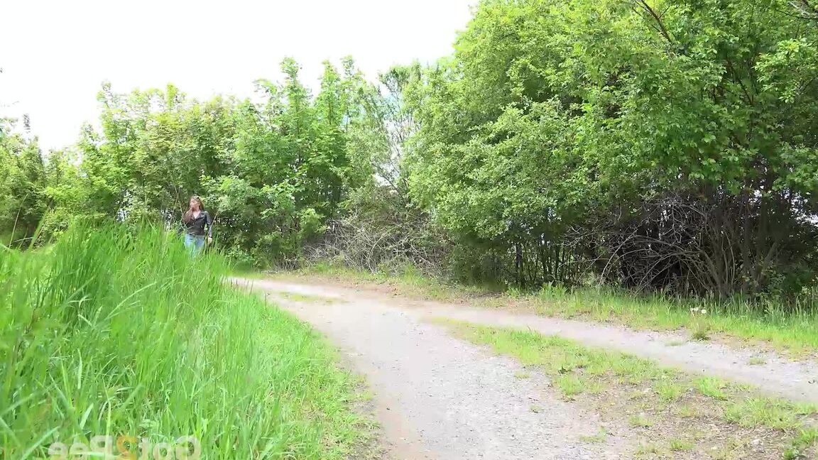 15P Die bekleidete Frau Dafne zieht ihre Jeans herunter, um auf einer Landstraße zu pinkeln
