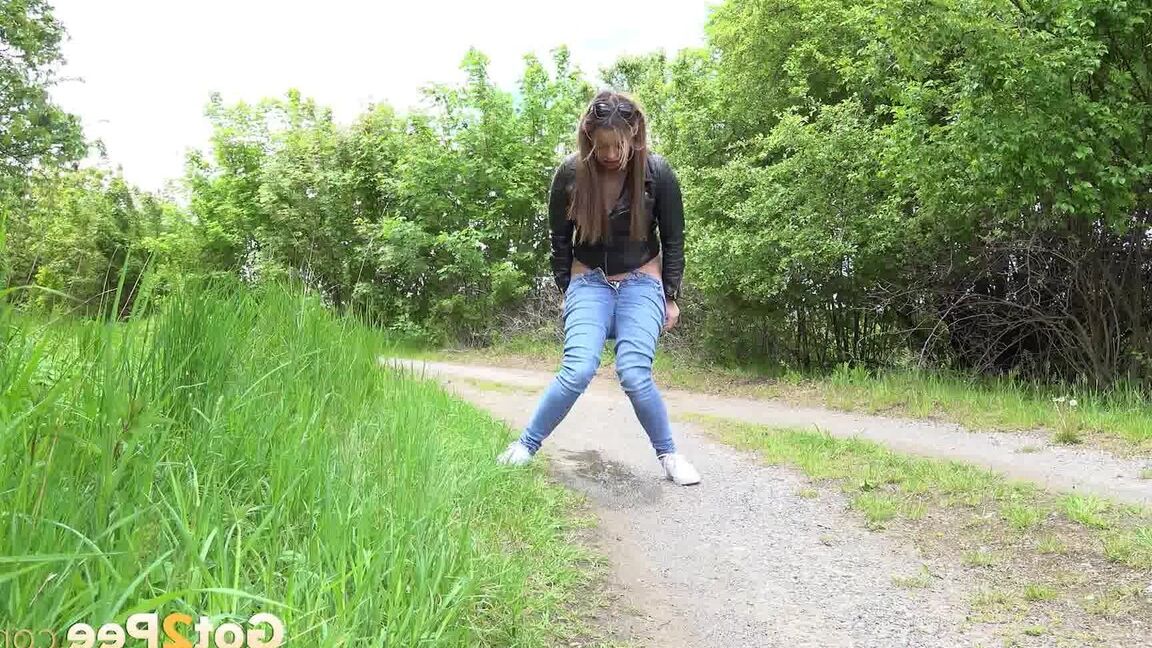 15P Die bekleidete Frau Dafne zieht ihre Jeans herunter, um auf einer Landstraße zu pinkeln