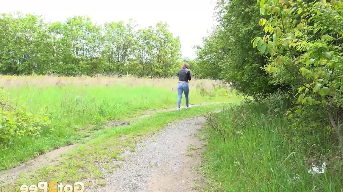 15P Die bekleidete Frau Dafne zieht ihre Jeans herunter, um auf einer Landstraße zu pinkeln