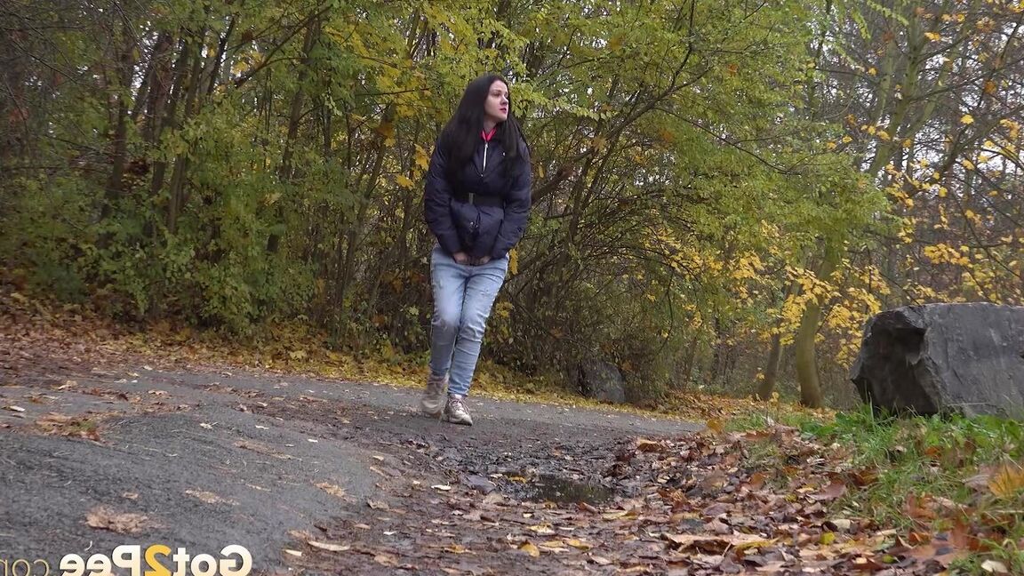 15P Garota de cabelos escuros abaixa a calça jeans para mijar enquanto sai para passear