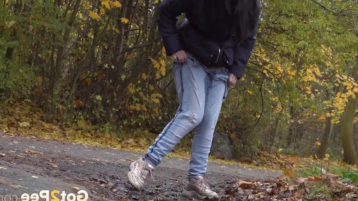 15P Garota de cabelos escuros abaixa a calça jeans para mijar enquanto sai para passear