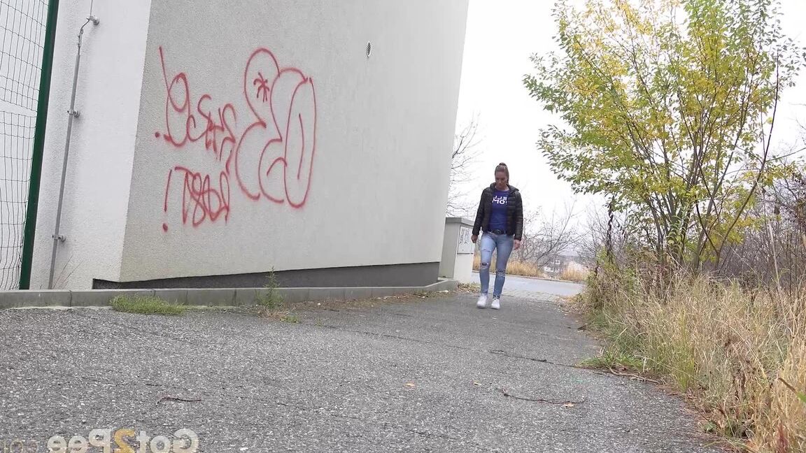 15P Czechoslovakian female Naomi Bennet takes a pee on pavement beside a building