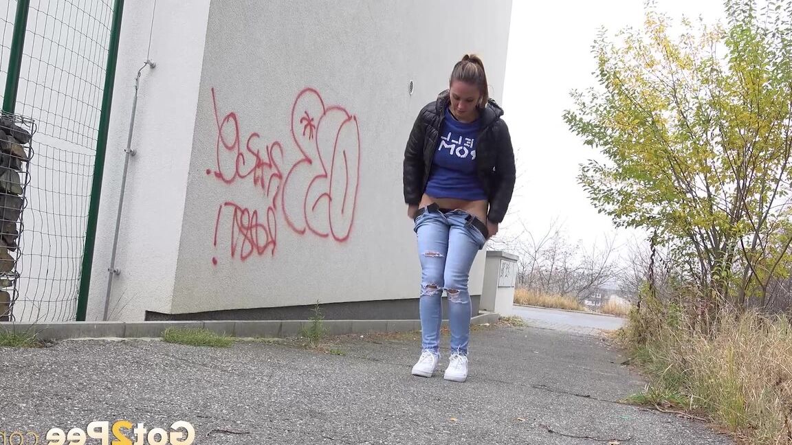 15P Czechoslovakian female Naomi Bennet takes a pee on pavement beside a building