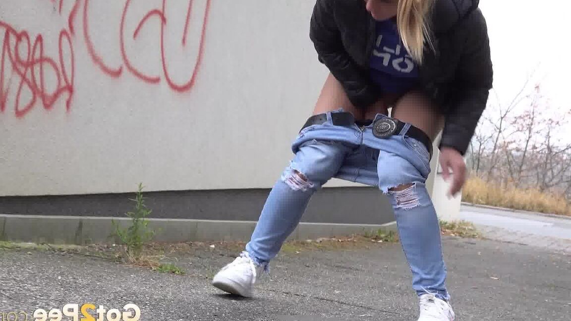 15P Czechoslovakian female Naomi Bennet takes a pee on pavement beside a building