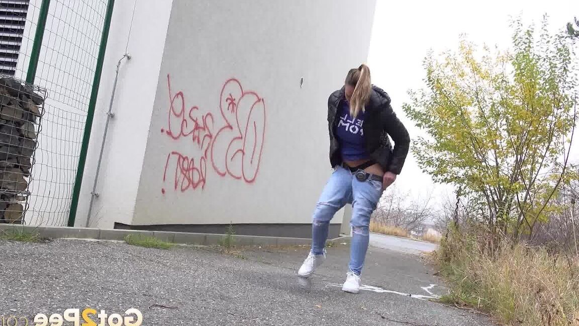 15P Czechoslovakian female Naomi Bennet takes a pee on pavement beside a building