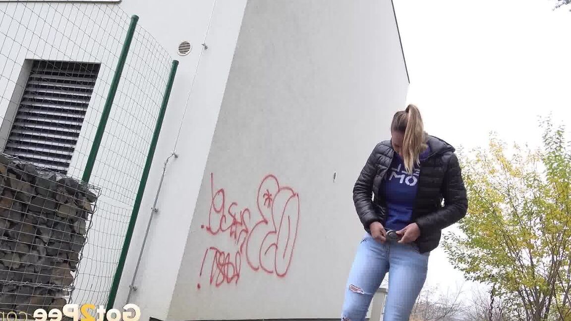 15P Czechoslovakian female Naomi Bennet takes a pee on pavement beside a building