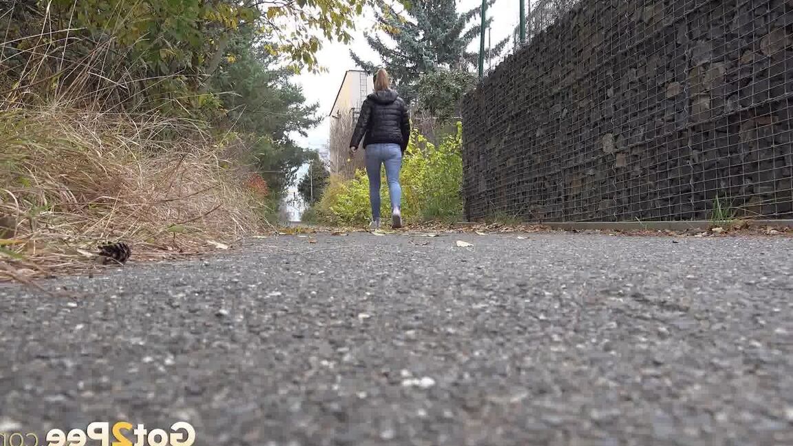 15P Czechoslovakian female Naomi Bennet takes a pee on pavement beside a building