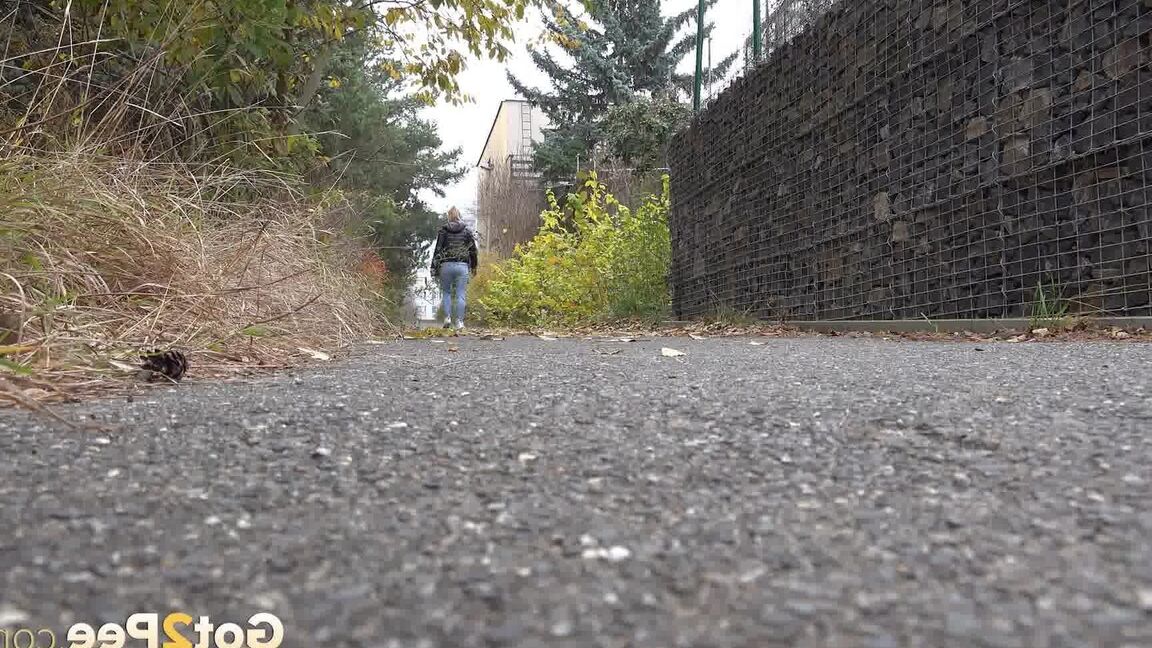 15P Czechoslovakian female Naomi Bennet takes a pee on pavement beside a building