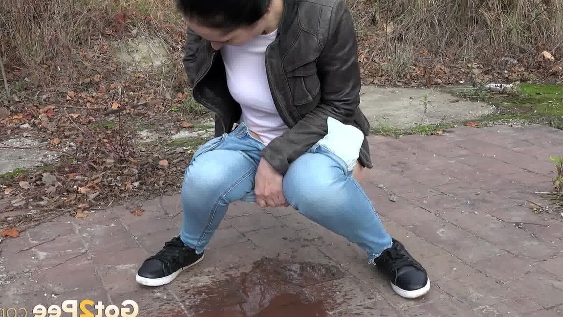 15P La femme vêtue, Corin, baisse son jean pour pisser d'urgence sur un terrain vague
