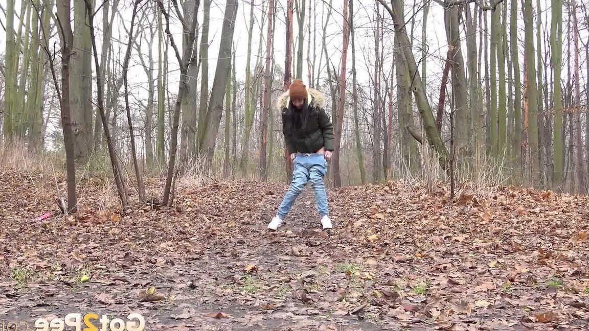 15P Dark-haired girl squats for a pee on leaf covered ground on a chilly day