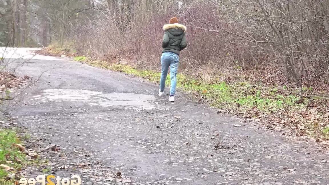 15P Dark-haired girl squats for a pee on leaf covered ground on a chilly day