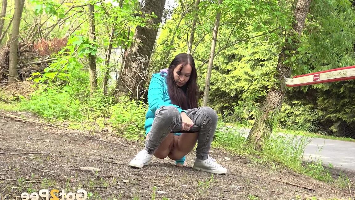 15P Short taken girl squats to be on a path in the woods while wearing a coat
