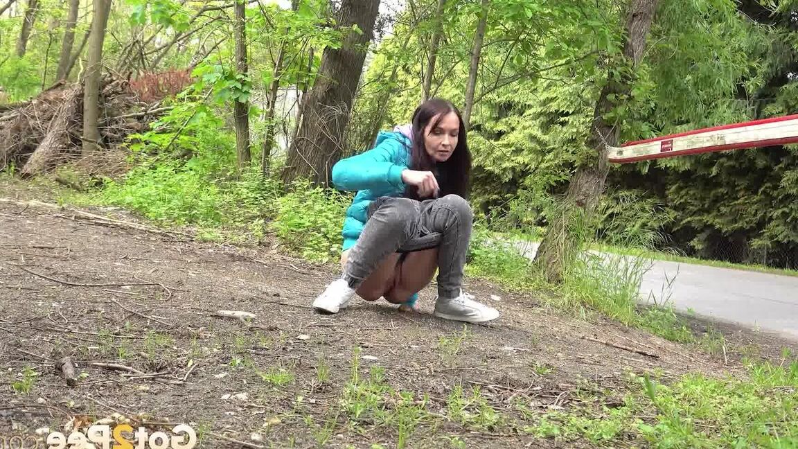 15P Short taken girl squats to be on a path in the woods while wearing a coat