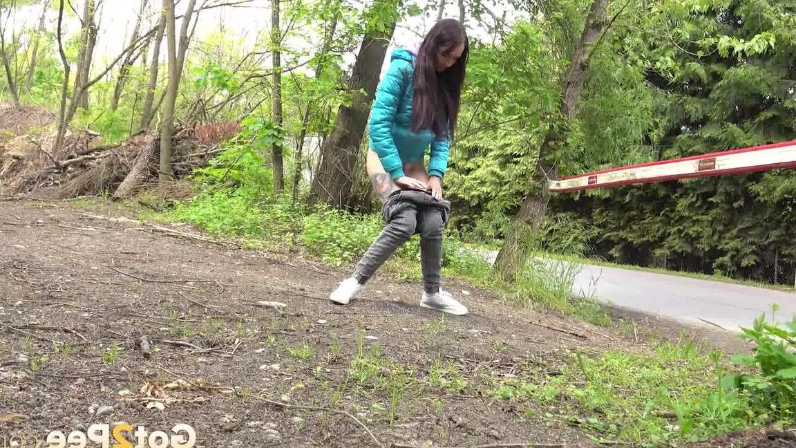 15P Short taken girl squats to be on a path in the woods while wearing a coat