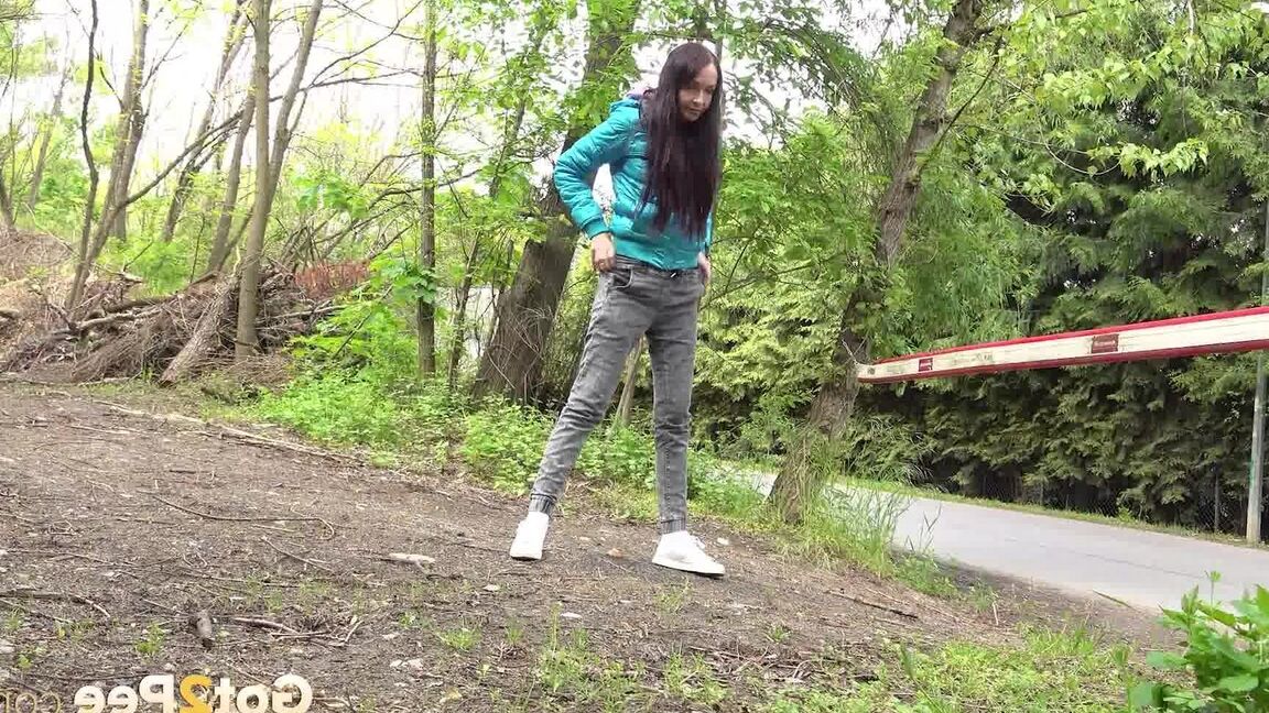 15P Short taken girl squats to be on a path in the woods while wearing a coat