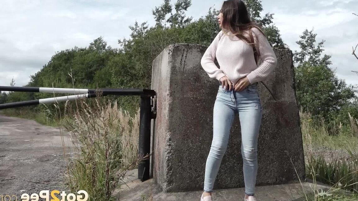 15P 服を着た女の子サーシャが小道のコンクリートブロックの後ろでしゃがんで小便をする