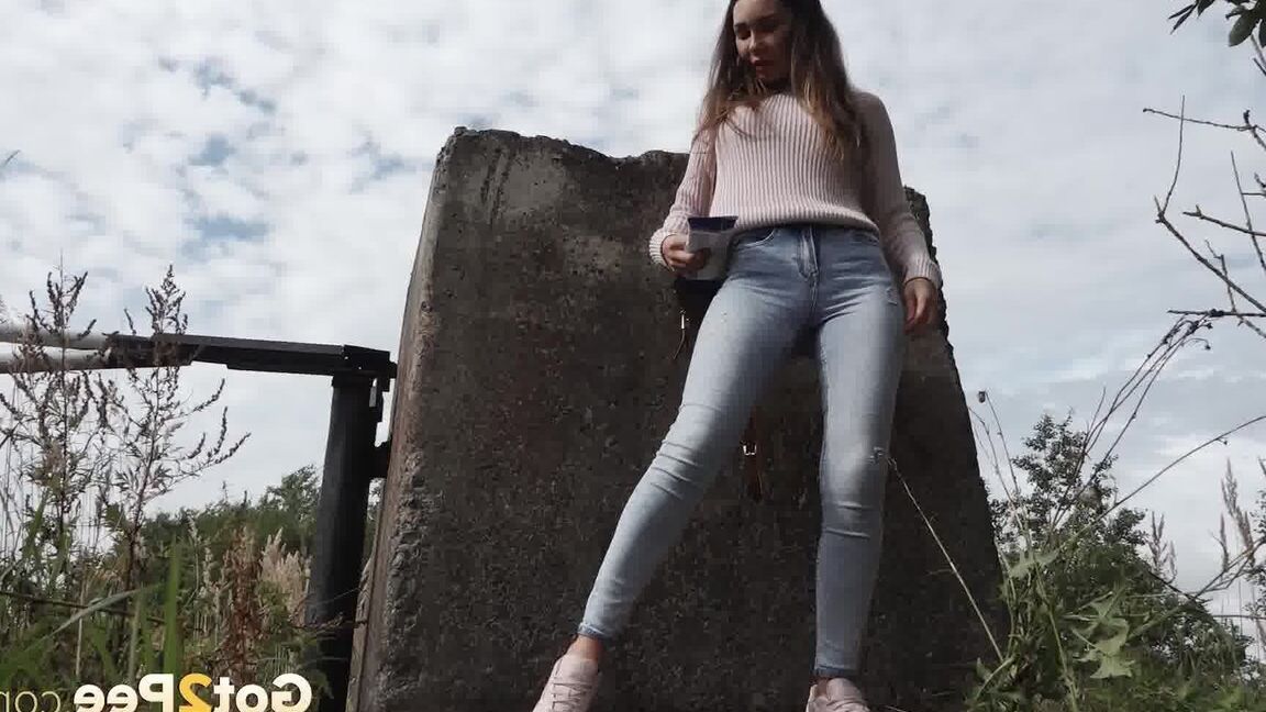15P 服を着た女の子サーシャが小道のコンクリートブロックの後ろでしゃがんで小便をする