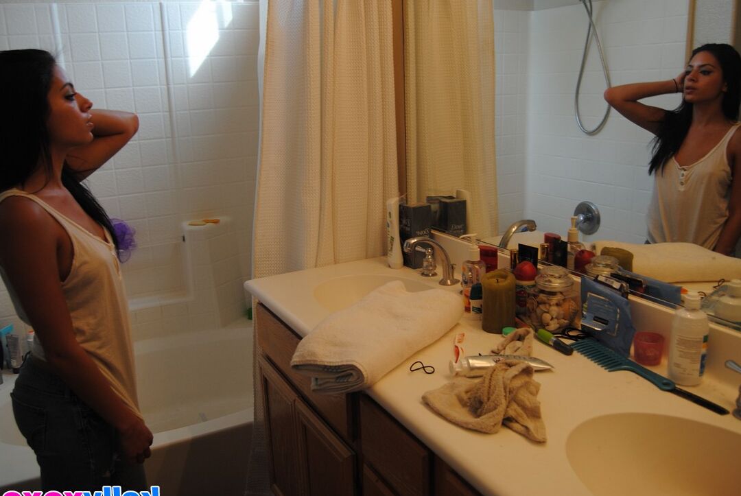 16P Kelly Xoxo, une fille aux cheveux longs, relève ses cheveux en prenant une douche