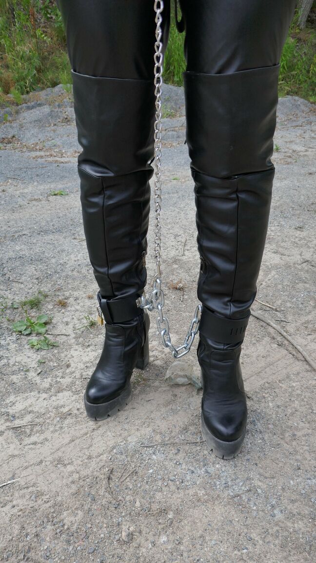 16P Collared female is restrained with cuffs and chains while wearing leather