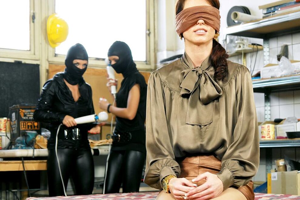 15P Rothaarige mit verbundenen Augen wird von Lesben in Catsuits und Kapuzen masturbiert