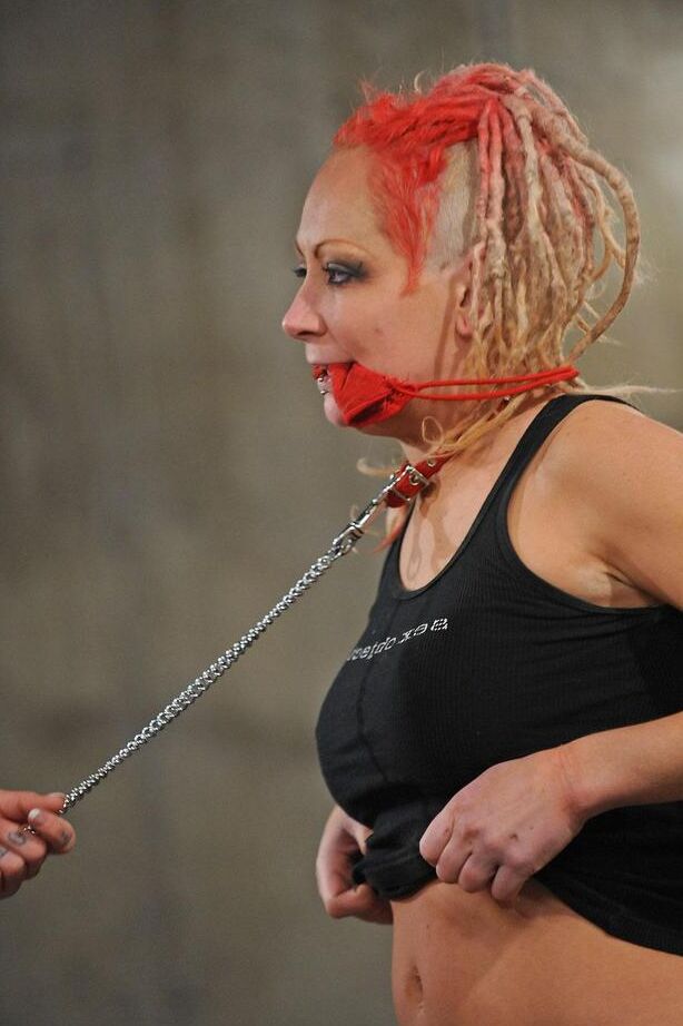 16P Une gouine potelée en robe rouge et des bottes noires domine son amante lesbienne