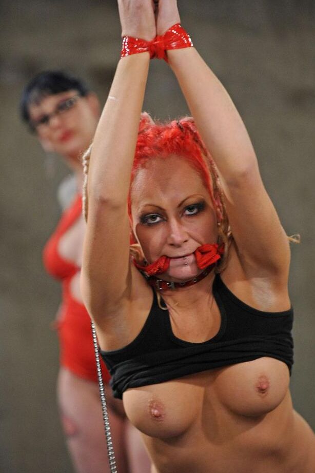 16P Une gouine potelée en robe rouge et des bottes noires domine son amante lesbienne