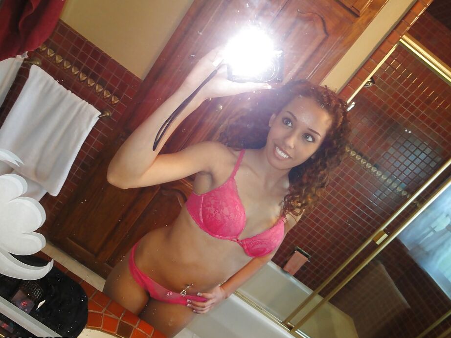 12P Latina de cabelos cacheados tirando a lingerie rosa e fazendo selfies
