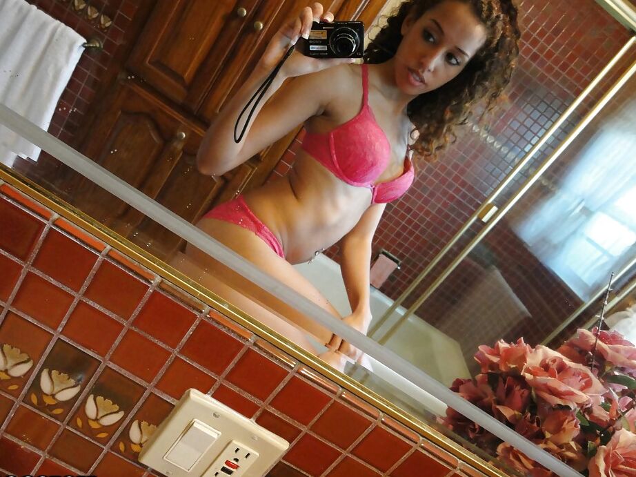 12P Latina de cabelos cacheados tirando a lingerie rosa e fazendo selfies