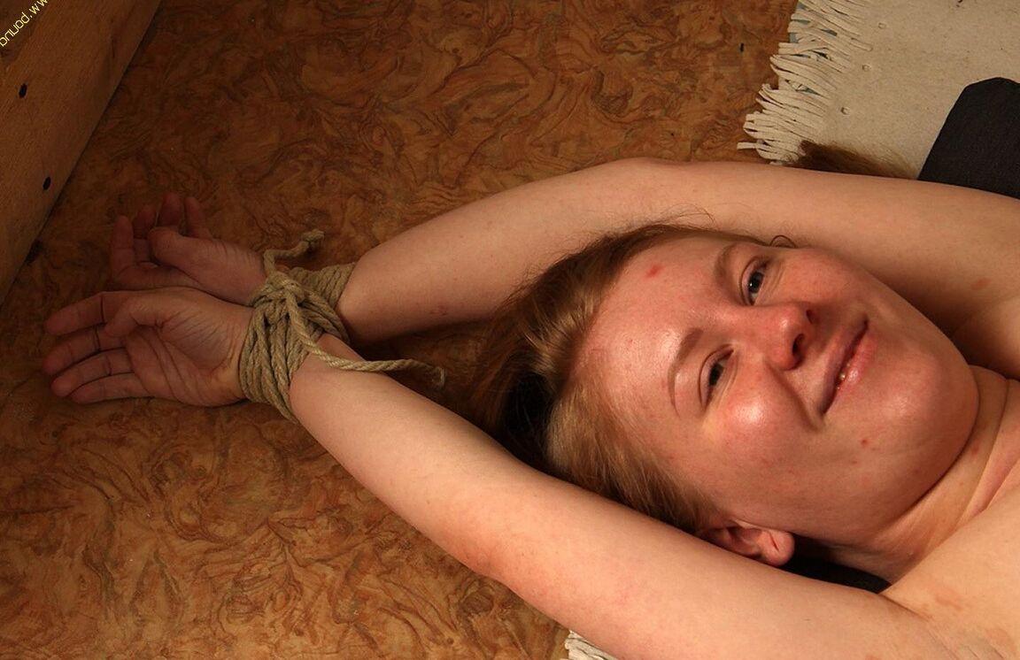 16P Topless girl is rendered helpless with her feet placed into stocks