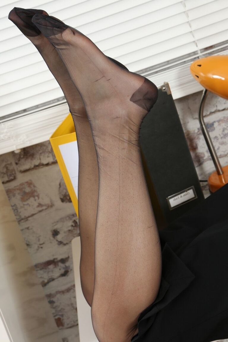 21P Ginger Celeste dangles her shoe and poses in black stockings at the office