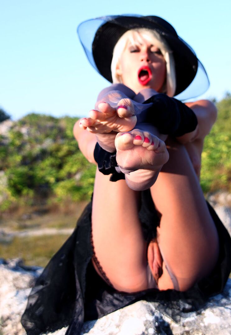 16P Classy woman Eva Diangelo releases her feet from heels and hose on a boulder