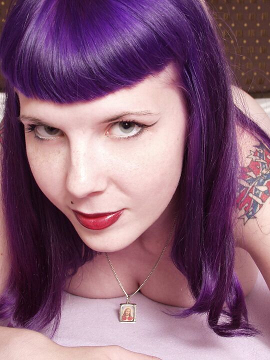 Das 16P-Gothic-Girl Szandora macht sich völlig nackt auf einem Bett aus und trägt dabei lila Haare