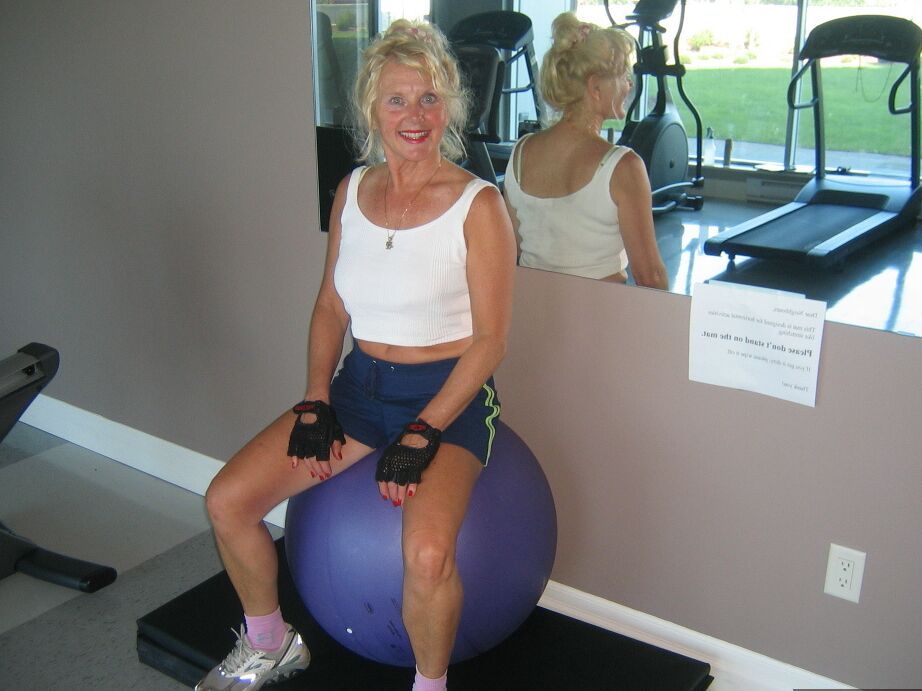 20P Mature blonde Ruth uncovers her breasts while working out at a gym