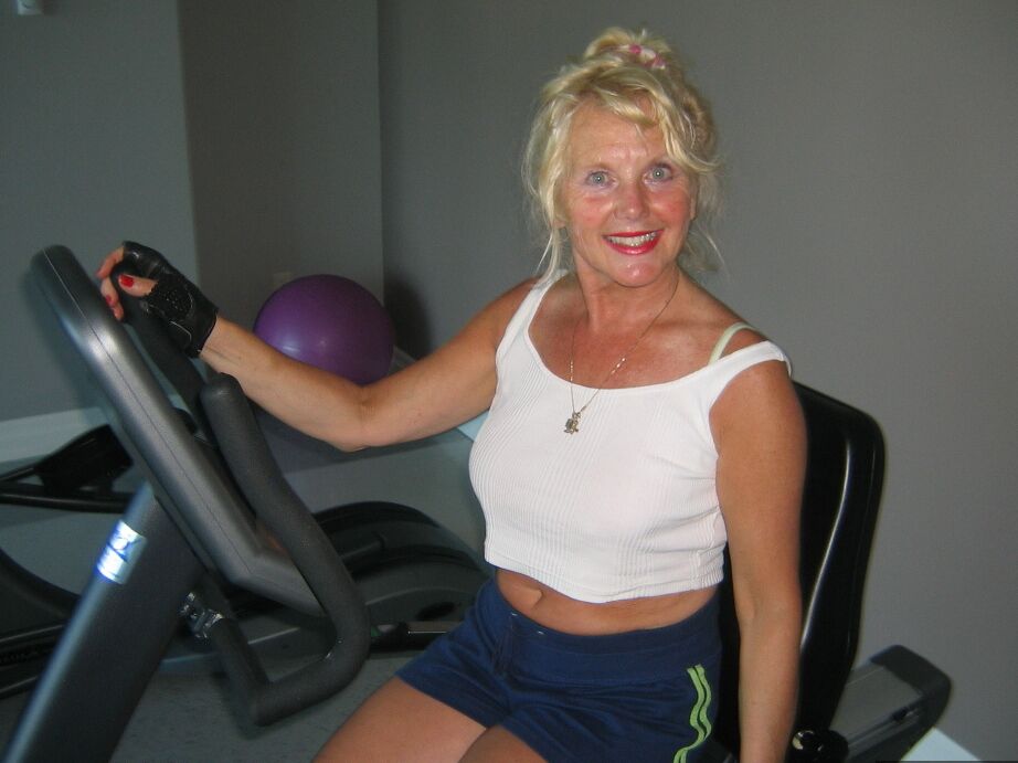 20P Mature blonde Ruth uncovers her breasts while working out at a gym