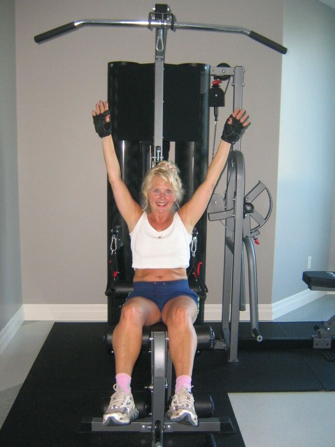 20P Mature blonde Ruth uncovers her breasts while working out at a gym